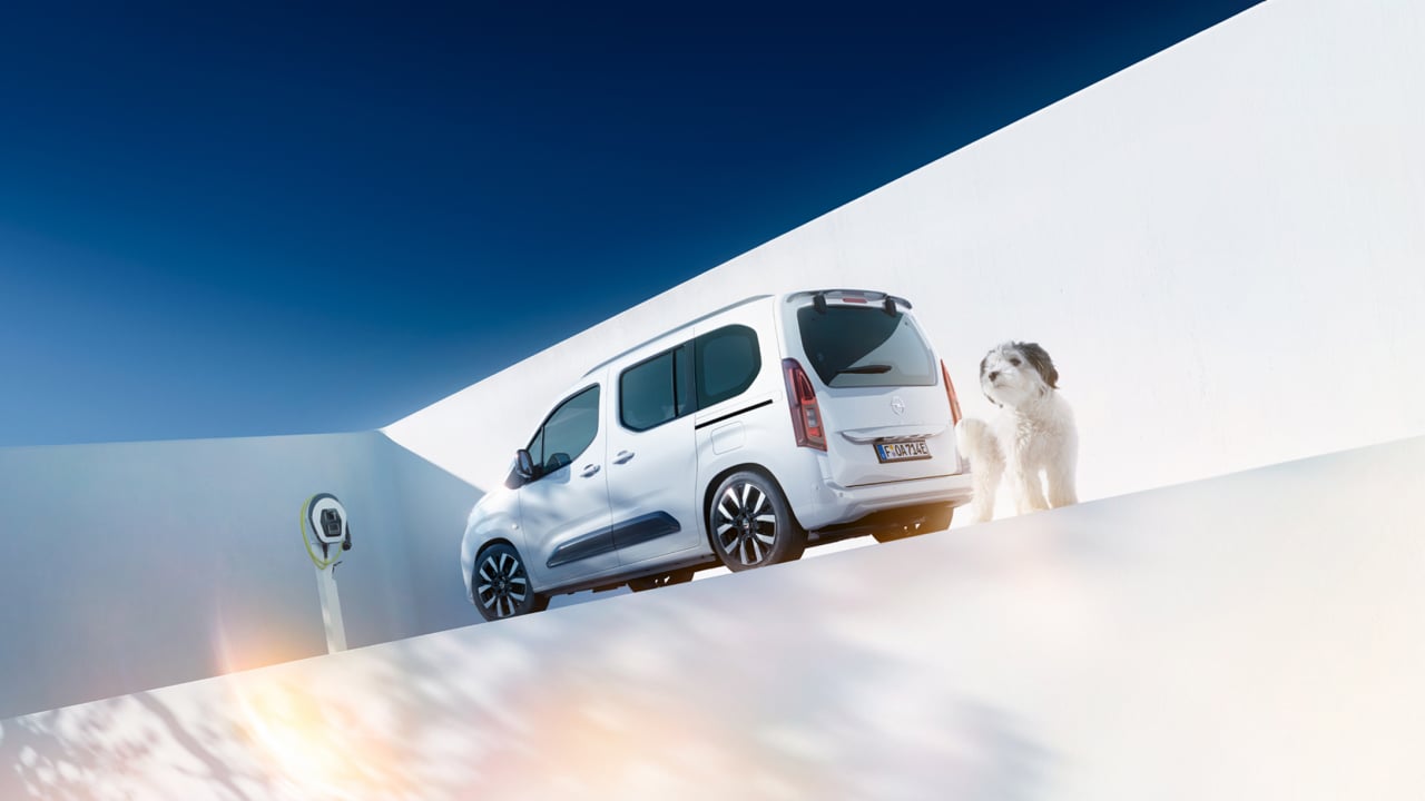 Pogled sa stražnje strane na bijeli Opel Combo Electric i psa pokraj Wallbox punjača